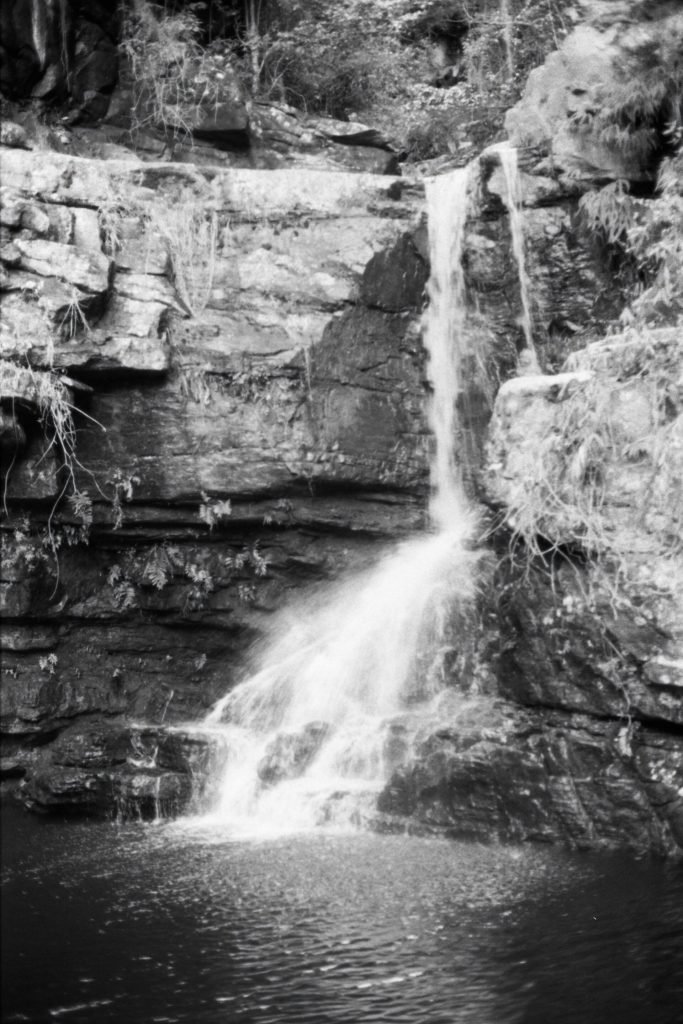 Fotografia em preto e branco da queda d'água caindo em poço entre paredões