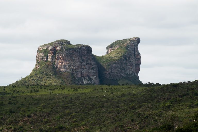 Formação rochosa de dois picos no meio de campo verde
