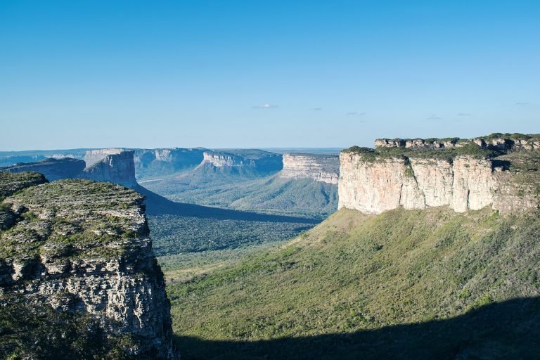 Paredões de arenito e morros de topo plano sobre vale verde, vistos do topo do Morro do Pai Inácio