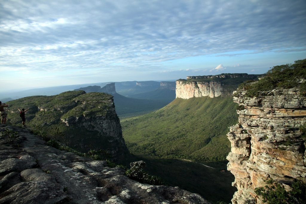 Borda rochosa do mirante com vista para morro de topo plano e vale ao fundo